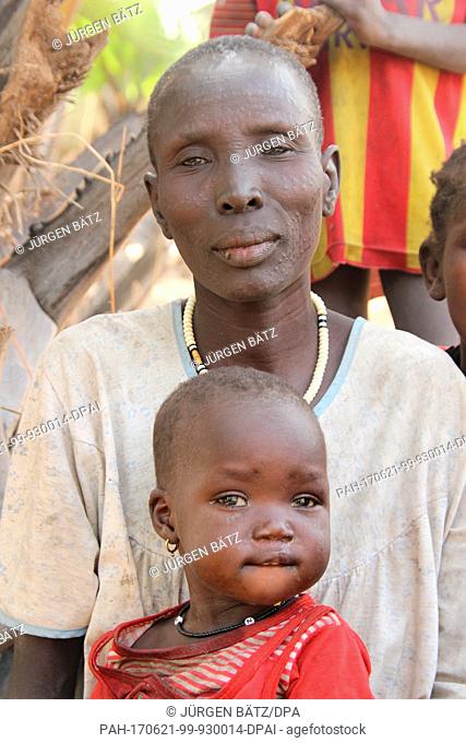 Internally displaced Nyakume Wuor Gai stands together with her youngest daughter in front of a shed on an island near Nyal at the federal state Unity, Uganda