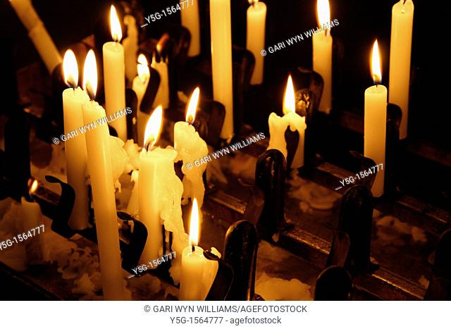 many lit candles in dark room in church