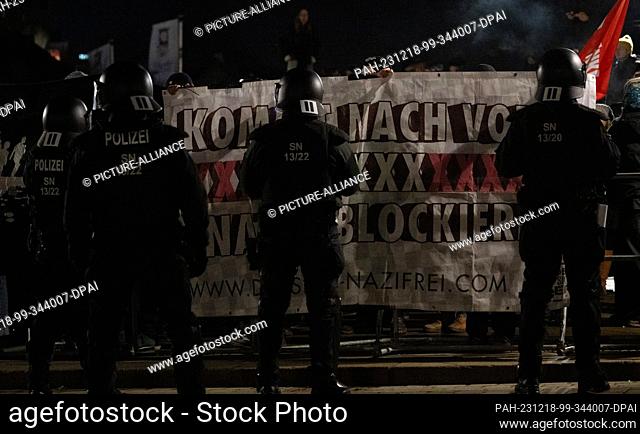 18 December 2023, Saxony, Dresden: Police officers stand in front of counter-demonstrators at the edge of a rally of the right-wing extremist movement Pegida on...