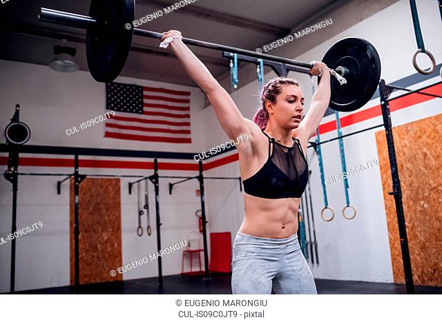 Young woman lifting barbell in gym