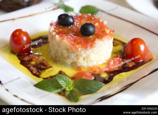 Cod fish salad with tomato and olive oil decorated with mint leaf Spain