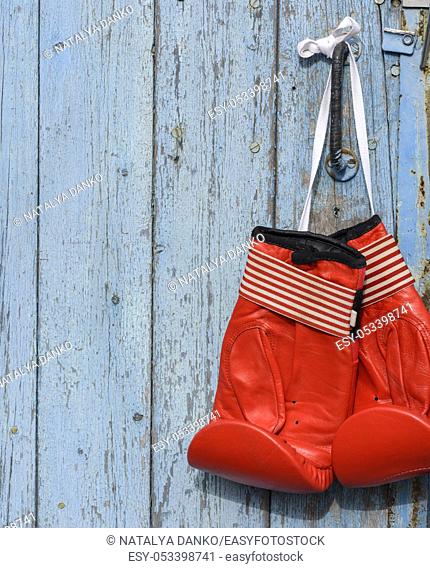 pair of red leather boxing gloves hanging on an old blue wooden wall, copy space