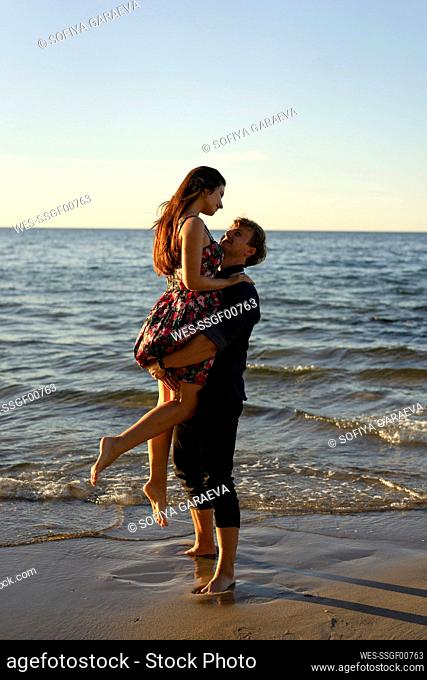 Boyfriend lifting girlfriend at beach on sunny day