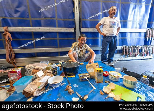 13 September 2023, Hesse, Gräfenhausen: Truck drivers from Tajikistan sit and stand in the parking lot of the Gräfenhausen service area at a makeshift dining...