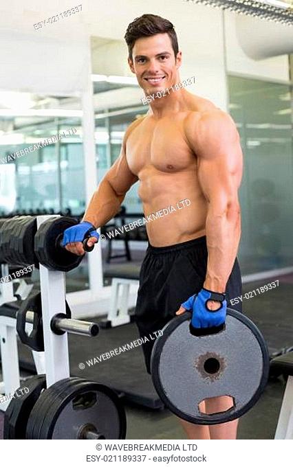 Shirtless muscular man lifting weight in gym