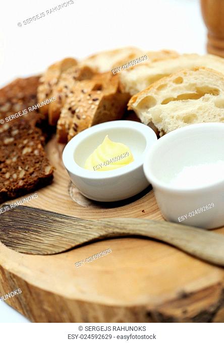 Two different types of bread with sour cream and a wooden spoon lying on a wooden plate