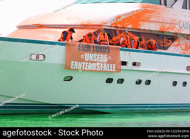 20 June 2023, Schleswig-Holstein, Neustadt in Holstein: Participants of a protest action stand with banners on a yacht in the harbor of Neustadt
