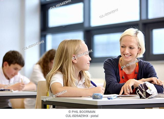 Teacher working with schoolgirl in classroom