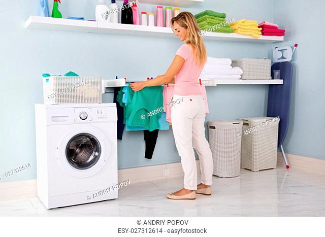 Woman Hanging Wet Clean Cloth On Clothes Line At Laundry Room
