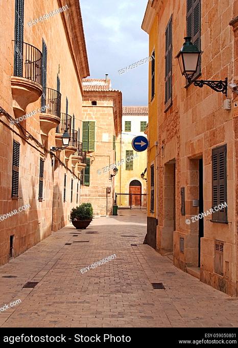 A quiet empty picturesque cobbled narrow street in ciutadella menorca with balconies and street lamps on colorful old houses