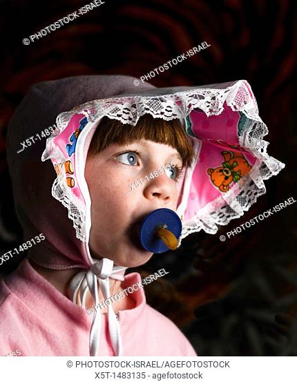 Young girl of 6 dressed up as a baby with pacifier in her mouth
