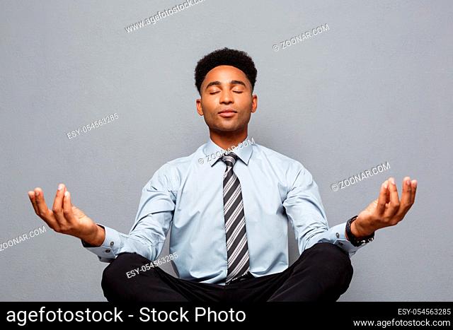 Business Concept - portrait of african american businessman doing meditation and yoga in before working