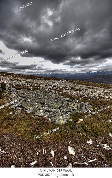 View from Morrone hill towards Highland munros with visible snowy tops against dramatic sky snd typical rocks and vegetation in spring