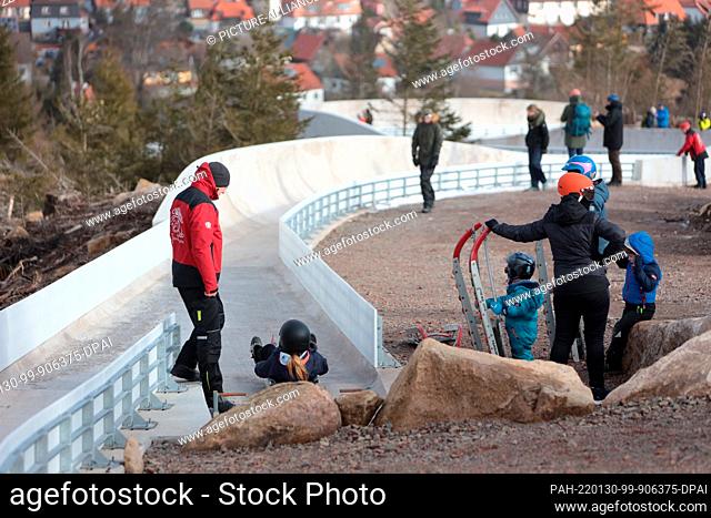 30 January 2022, Saxony-Anhalt, Schierke: Visitors ride on racing sleds during a trial sledding action on the new luge track in Schierke