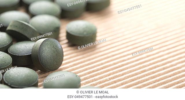 Detail of many organic spirulina tablets with low depth of field over cardboard background