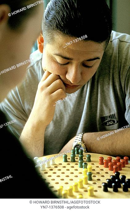 close up of player as he ponders his next move on the chinese chequers board