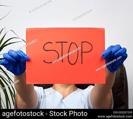 female medic is sitting in a brown leather chair in the office holding a red sheet of paper with the words stop, concept is not to panic, keep calm