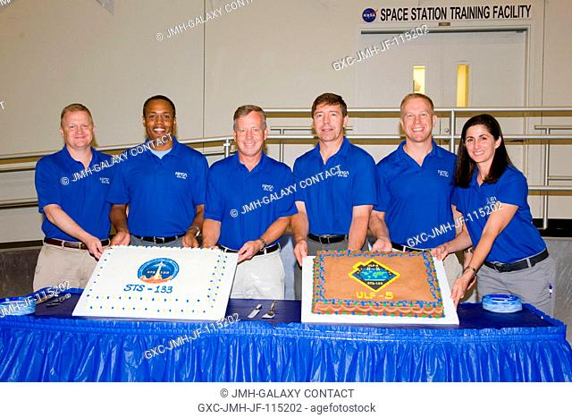 STS-133 crew members pose for a photo during a cake-cutting ceremony in the Jake Garn Simulation and Training Facility at NASA's Johnson Space Center