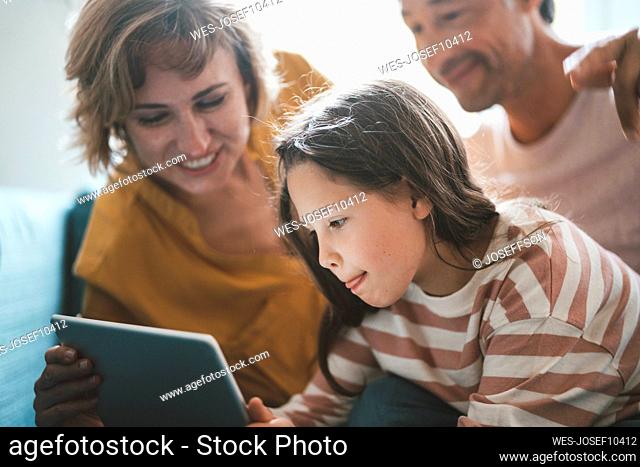 Girl using tablet PC by father and mother at home