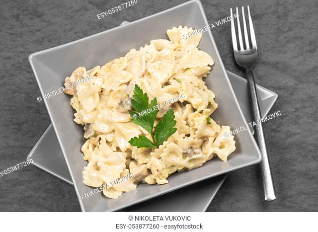 Pasta in cheese sauce with parsley Italian food in gray plate on gray background