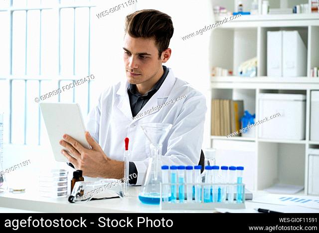 Serious male scientist holding digital tablet while working in laboratory
