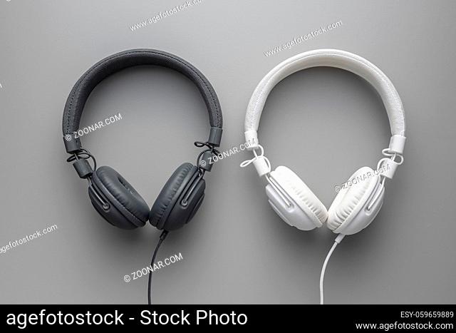 White and black wired stereo headphones on gray background. Top view