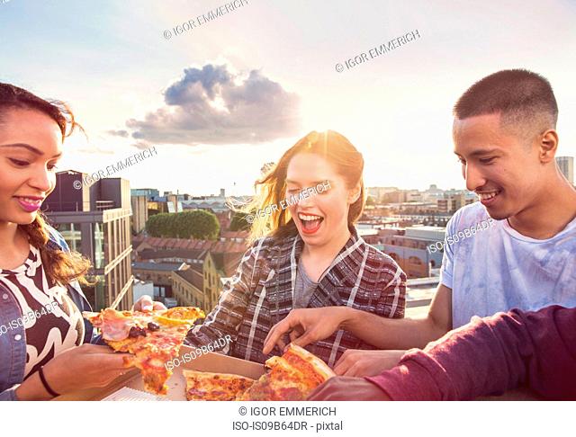 Young adult friends sharing pizza at roof party in London, UK