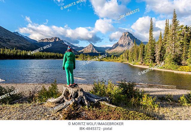 Young woman looking at mountain lake Two Medicine Lake in mountain landscape, back Sinopah Mountain, Glacier National Park, Montana, USA