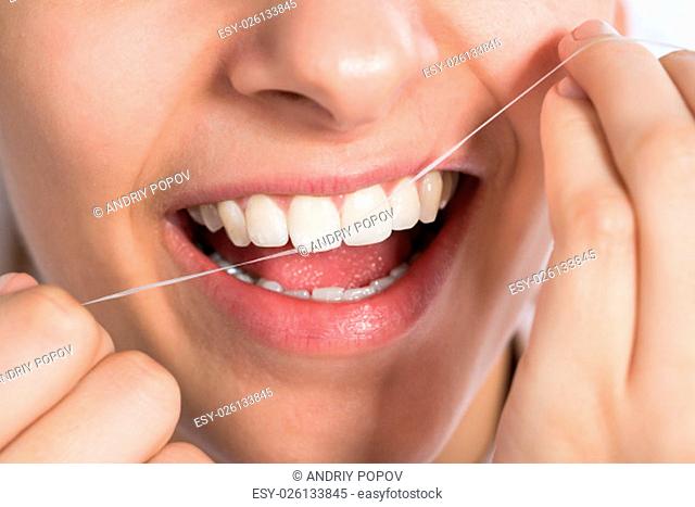 Closeup of young woman flossing teeth at home