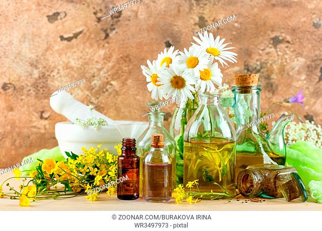 Mortar with fresh wild flowers and essential oil in glass bottles