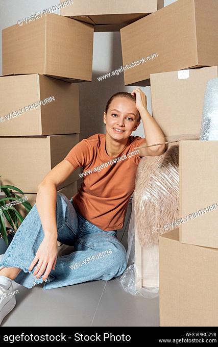 Young woman leaning by cartons at new home