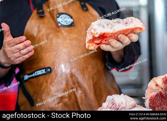 PRODUCTION - 16 June 2021, North Rhine-Westphalia, Münster: In a butcher shop, a butcher cuts up a previously slaughtered Wagyu steer