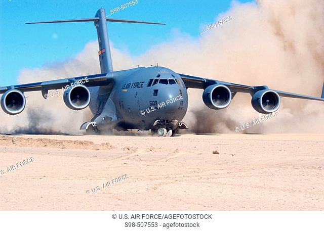 The jet engines of an Air Force C-17 Globemaster III kick up clouds of dust as the aircraft turns around at the end of a dirt runway at Bicycle Lake Army...