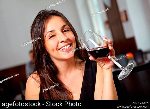 Lächelnde Frau mit einem Glas Rotwein im Restaurant