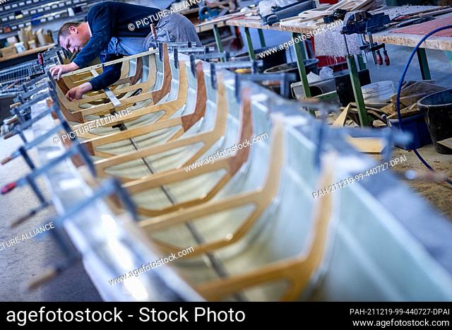 30 November 2021, Mecklenburg-Western Pomerania, Warin: Employees work in a hall of Baumgarten Bootsbau on rowing boats according to customer wishes