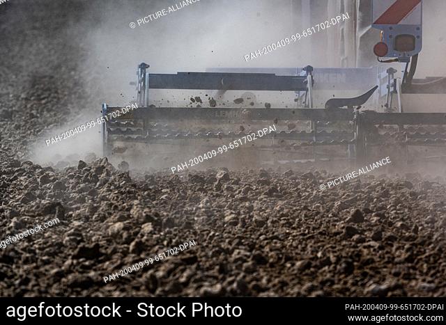09 April 2020, Bavaria, Sand: A farmer kicks up dust with his tractor while working a field. Photo: Armin Weigel/dpa. - Sand/Bavaria/Germany