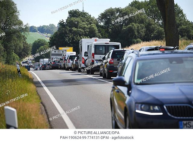 24 June 2019, Mecklenburg-Western Pomerania, Wolgast: Cars are crowded together on a country road in a long queue. The traffic jam is caused by a construction...