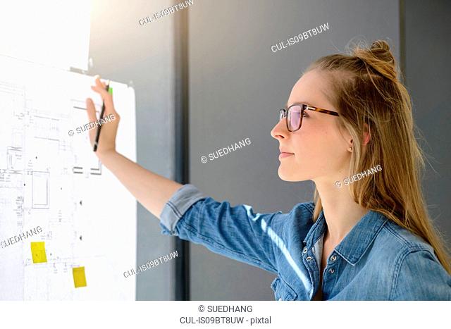Woman contemplating plans on glass wall