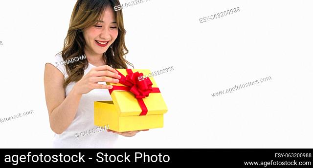 Young asian woman in white t-shirt opening a gift box received for a special occasion. Portrait on white background with studio light