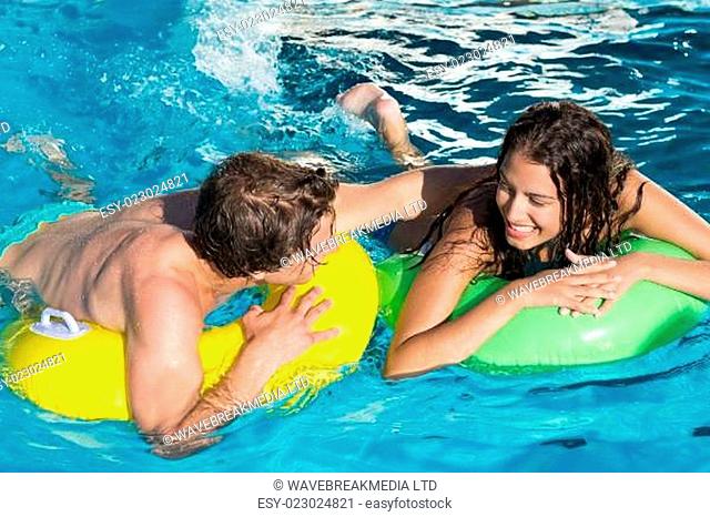 Couple in inflatable rings at swimming pool