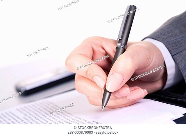 Photo of grey pen in hand over document at workplace