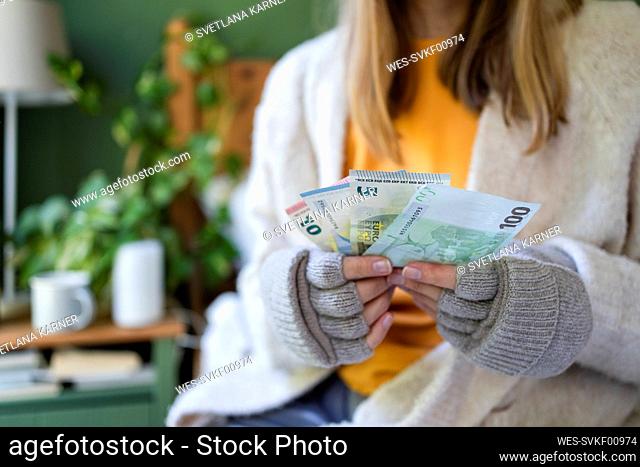 Hands of woman holding currency at home