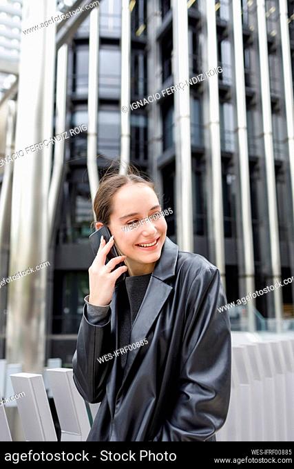 Smiling female entrepreneur talking on mobile phone in city