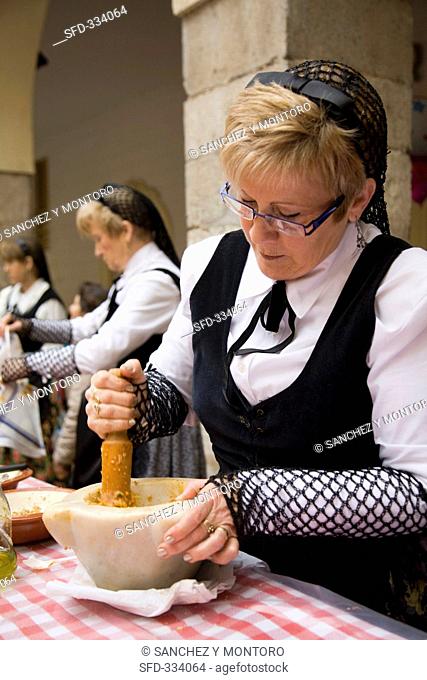 A woman in a traditional costume preparing sauce for calcotada Spain