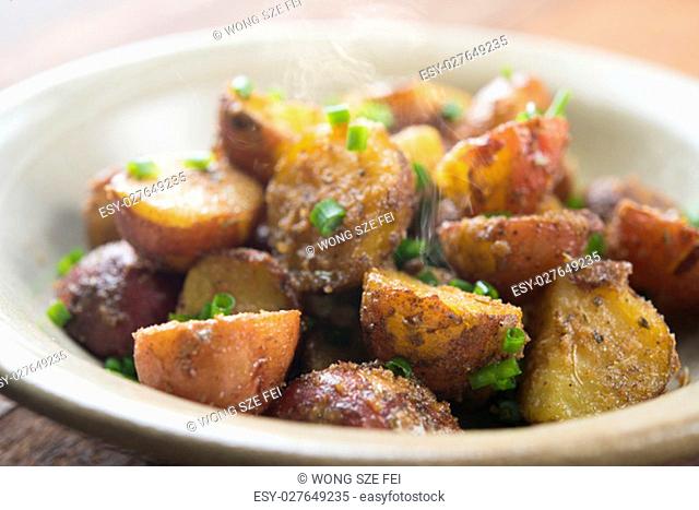 Freshly oven roasted baby potatoes with skin on plate, wooden table background