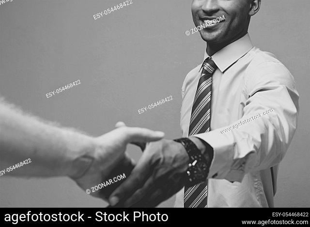 Business concept - Close-up of two confident business people shaking hands during a meeting.Black and white
