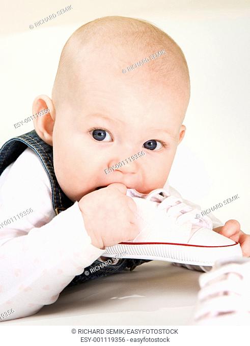 portrait of lying down baby girl holding a shoe
