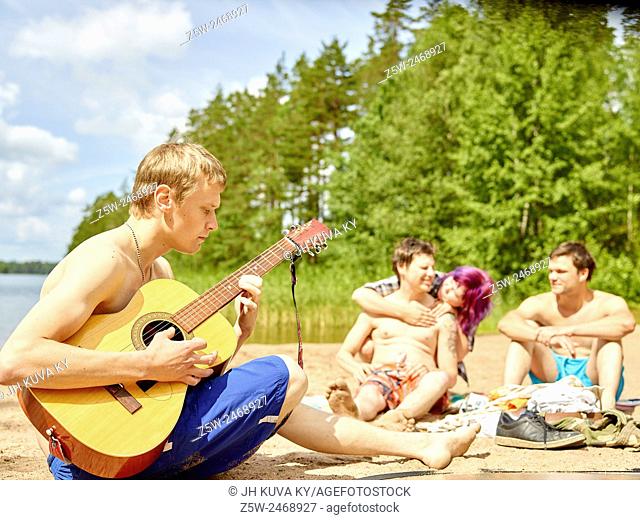 The group of the friends chilling out on the beach, summer day. Shot in southern Finland