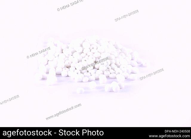 Beads spread on white background. Background or texture of beads. Close up, macro, It is used in finishing fashion clothes