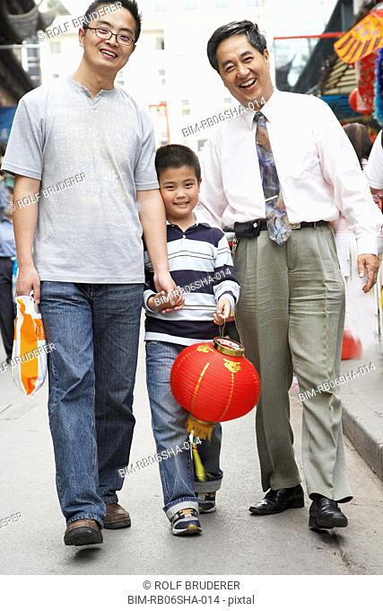 Asian grandfather, father and son walking on sidewalk
